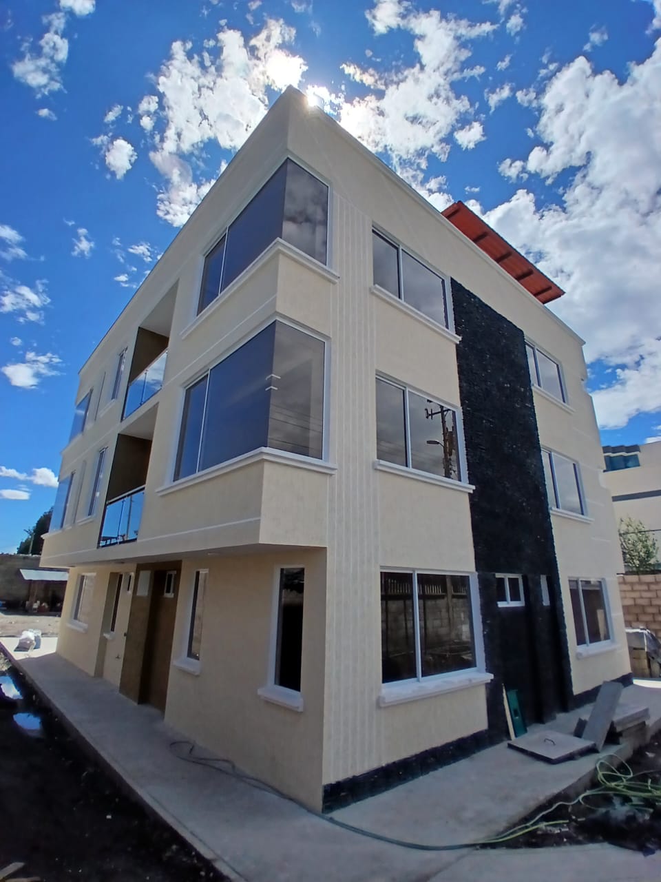 Edificio residencial de tres pisos con fachada moderna y ventanales